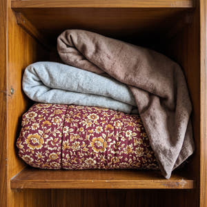 Before: a razai and two blankets stacked loose, filling the whole almari shelf